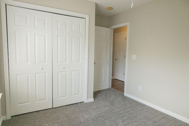 unfurnished bedroom featuring a closet, baseboards, and carpet flooring