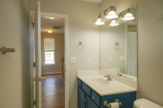 bathroom with visible vents, wood finished floors, vanity, baseboards, and toilet