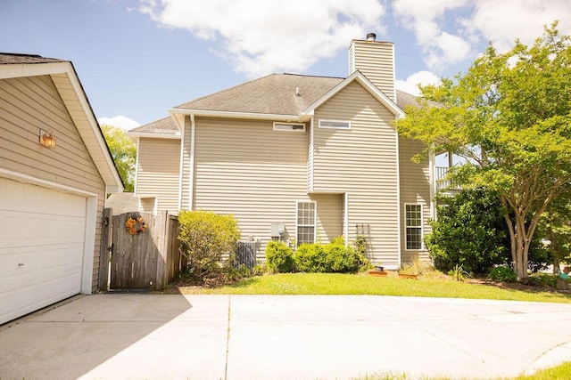 view of home's exterior featuring a garage, fence, a chimney, and concrete driveway