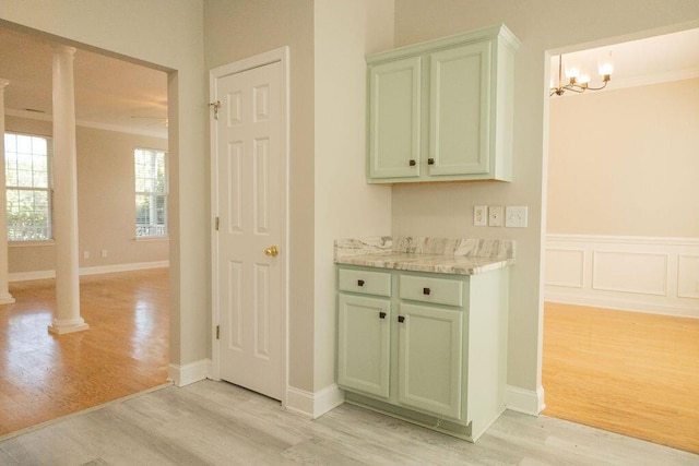 interior space with baseboards, ornate columns, light wood-style flooring, and a chandelier