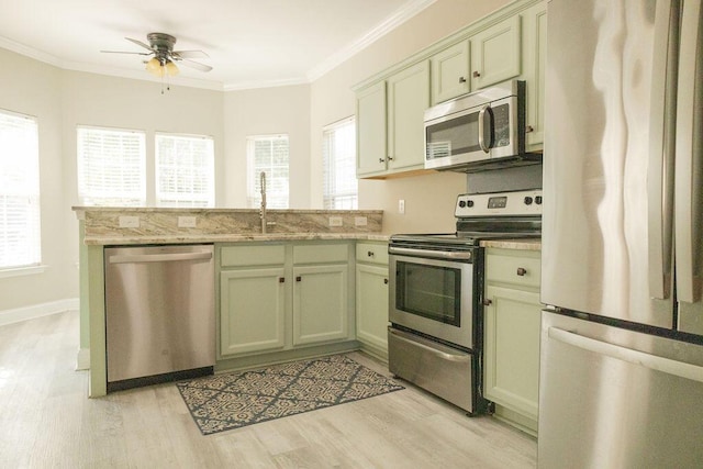 kitchen featuring ceiling fan, appliances with stainless steel finishes, a sink, light wood finished floors, and a peninsula