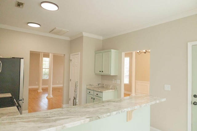 kitchen with light wood-type flooring, ornamental molding, plenty of natural light, and freestanding refrigerator