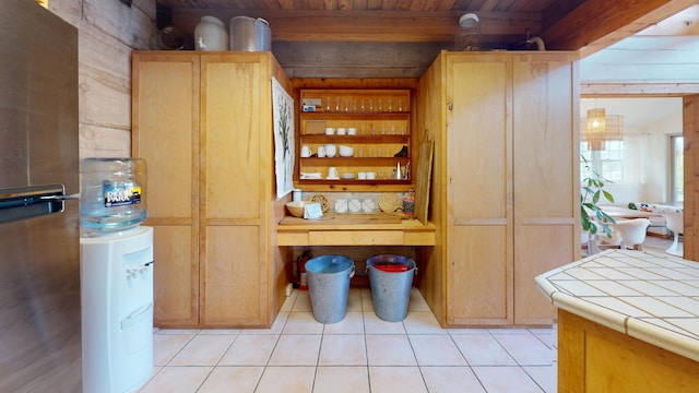 interior space with tile counters, wooden ceiling, stainless steel fridge, wood walls, and light tile patterned floors