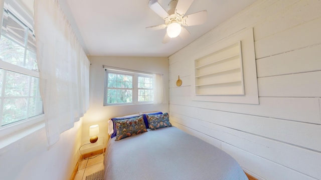 bedroom featuring vaulted ceiling, ceiling fan, and wooden walls