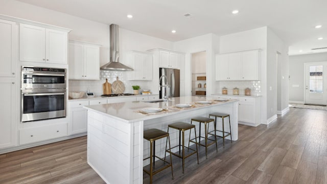 304 Archar St, Summerville, SC 29486 - kitchen featuring stainless steel appliances, wall chimney exhaust hood, backsplash, a center island with sink, and a kitchen breakfast bar
