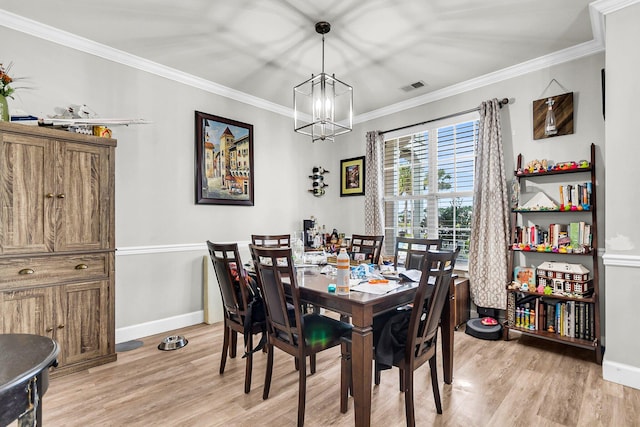 dining room with light hardwood / wood-style floors, a notable chandelier, and ornamental molding