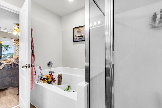 bathroom with plus walk in shower, hardwood / wood-style floors, and ceiling fan