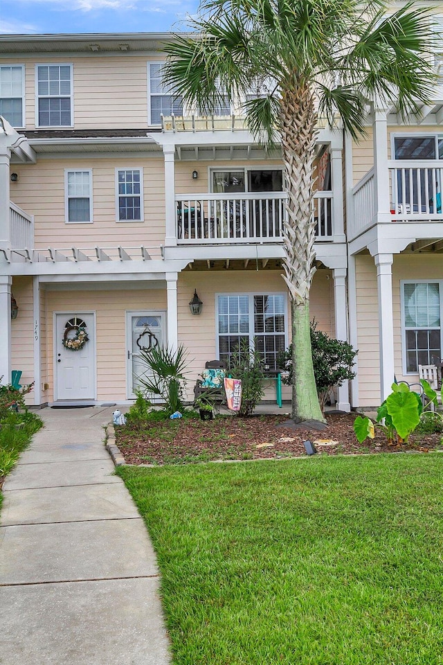 exterior space featuring a front lawn and a balcony