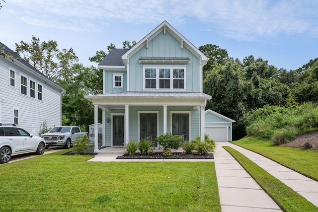 view of front of property with a front lawn, a garage, covered porch, and an outbuilding