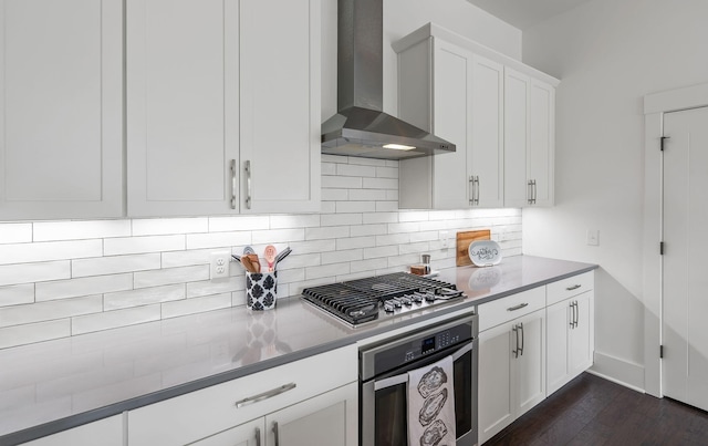 kitchen featuring wall chimney range hood, white cabinets, stainless steel appliances, and dark hardwood / wood-style floors