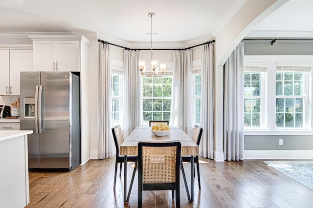 dining room with a chandelier, light wood-type flooring, and ornamental molding