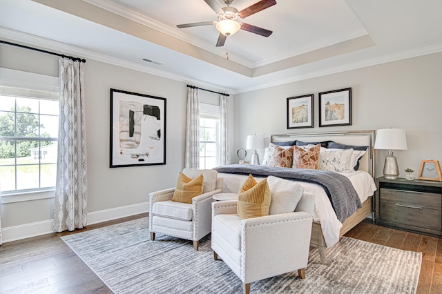 bedroom with hardwood / wood-style floors, a raised ceiling, and ceiling fan