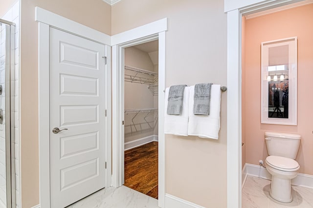 bathroom with toilet, walk in shower, and ornamental molding