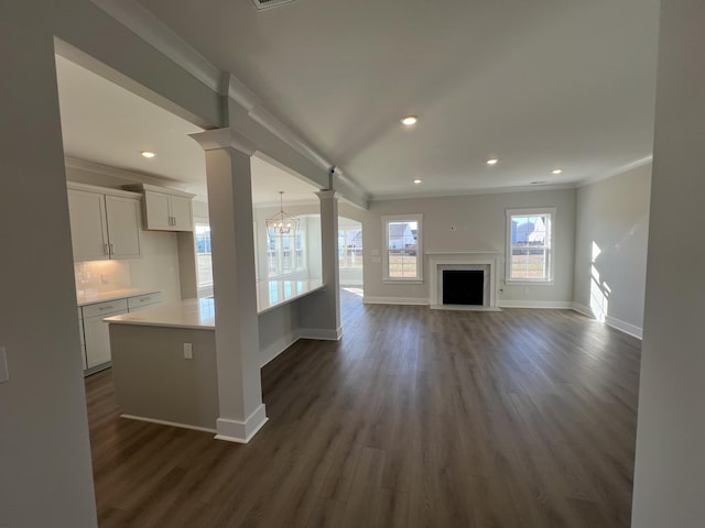 unfurnished living room with dark hardwood / wood-style flooring, decorative columns, an inviting chandelier, and ornamental molding