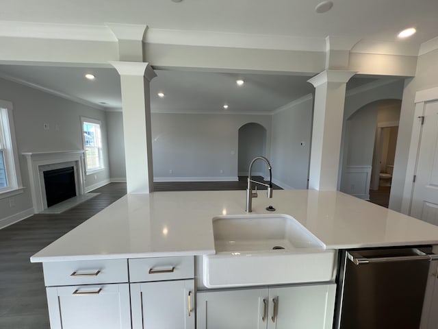 kitchen with a center island with sink, white cabinetry, sink, and ornamental molding