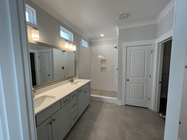 bathroom featuring tile patterned flooring, vanity, a tile shower, and crown molding