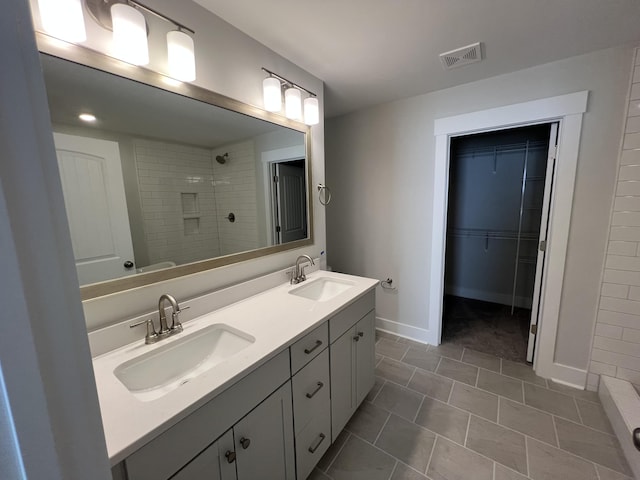 bathroom featuring tile patterned flooring, vanity, and tiled shower