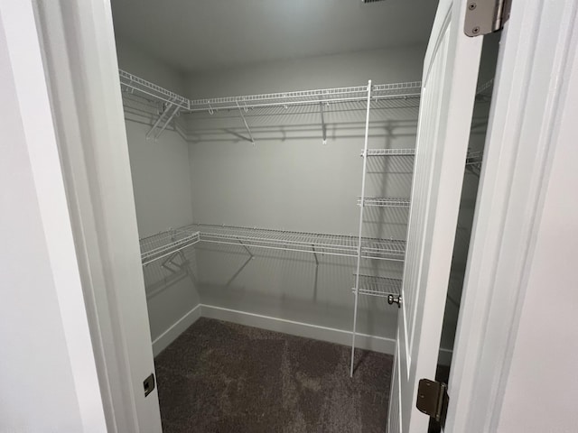 spacious closet featuring dark carpet