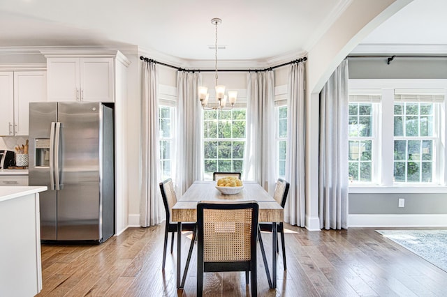 dining room with ornamental molding, light wood-type flooring, and a notable chandelier