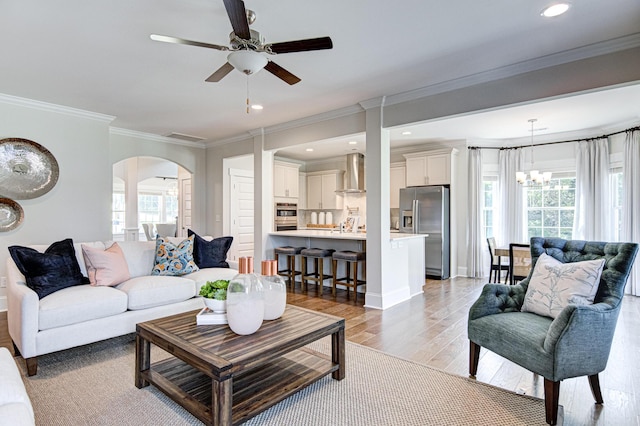 living room with ceiling fan with notable chandelier and crown molding