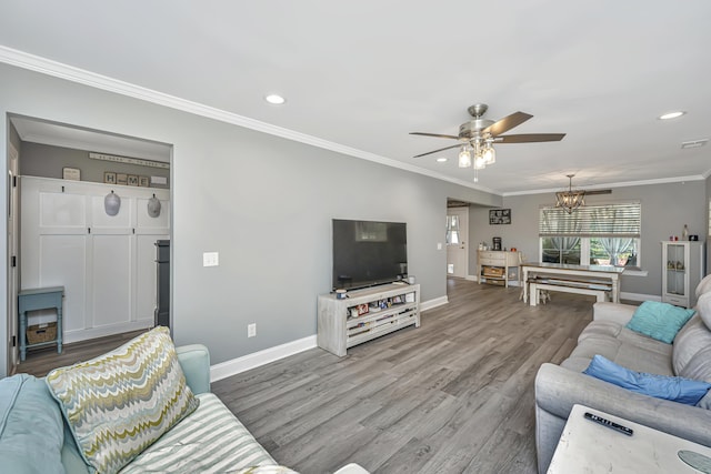 living room with crown molding, baseboards, recessed lighting, ceiling fan with notable chandelier, and wood finished floors