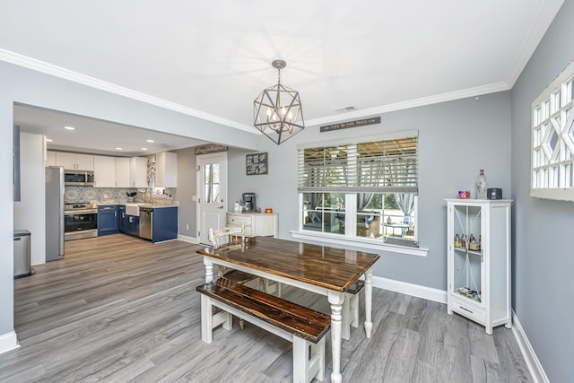 dining area with light wood finished floors, baseboards, crown molding, and an inviting chandelier