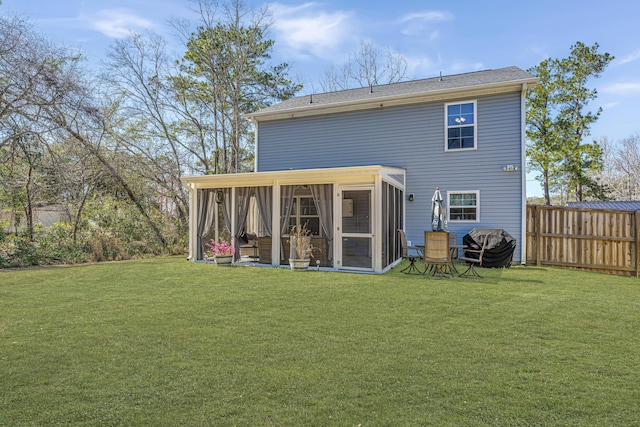 back of property with fence, a lawn, and a sunroom