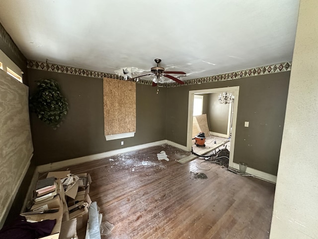 unfurnished room with ceiling fan with notable chandelier and wood-type flooring