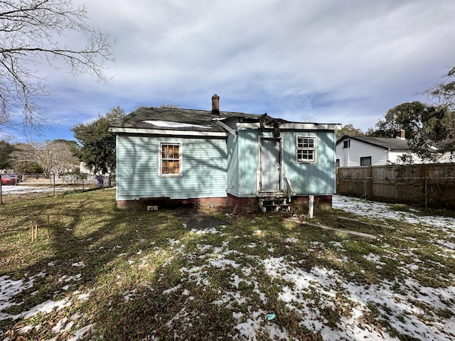 snow covered rear of property featuring a yard