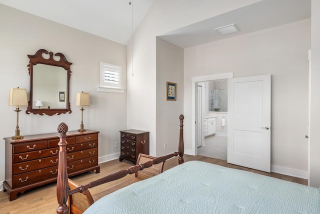 bedroom with connected bathroom, light hardwood / wood-style flooring, and lofted ceiling