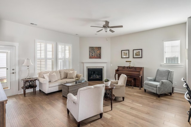 living room featuring ceiling fan, plenty of natural light, and light hardwood / wood-style floors