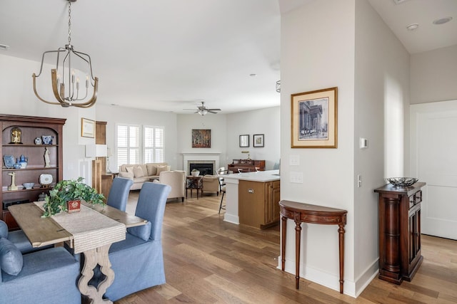 dining space featuring light wood-type flooring and ceiling fan with notable chandelier