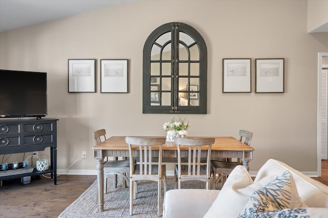 dining space featuring lofted ceiling, baseboards, and wood finished floors