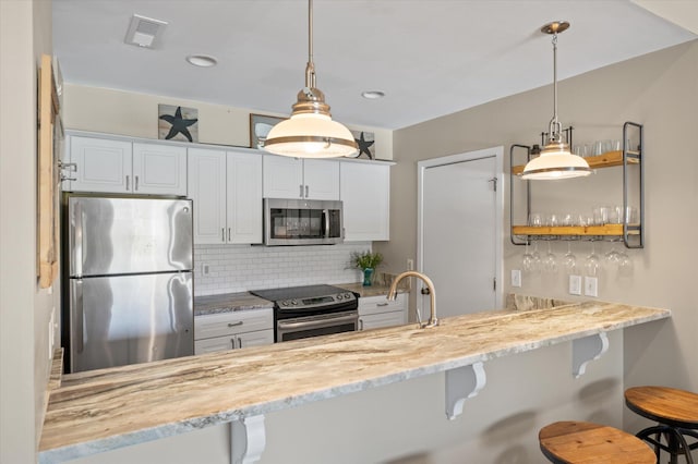 kitchen featuring visible vents, decorative backsplash, appliances with stainless steel finishes, a peninsula, and pendant lighting