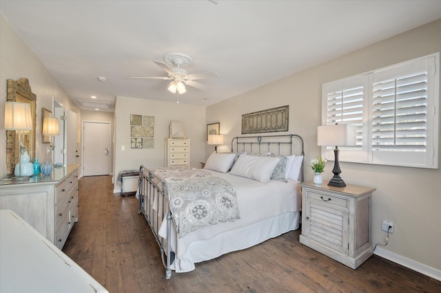 bedroom with a ceiling fan, attic access, baseboards, and dark wood-type flooring