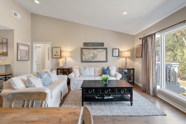 living room with baseboards, visible vents, lofted ceiling, wood finished floors, and recessed lighting