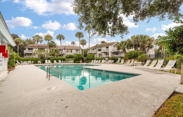 community pool with a residential view, fence, and a patio