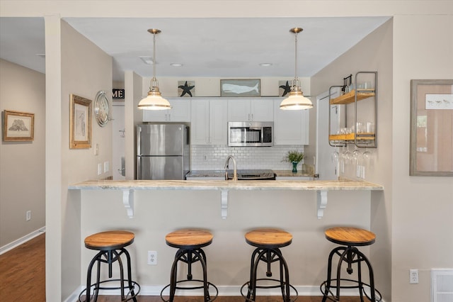 kitchen featuring appliances with stainless steel finishes, backsplash, pendant lighting, and a peninsula