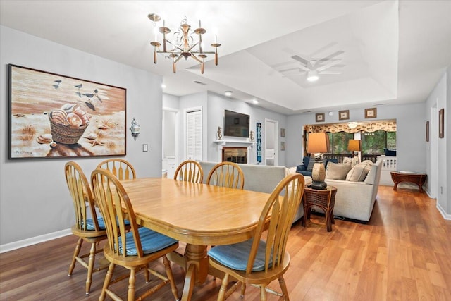 1025 Scaup Ct, Kiawah Island, SC 29455 - dining area featuring a raised ceiling, a chandelier, light wood-style flooring, ceiling fan, and a fireplace