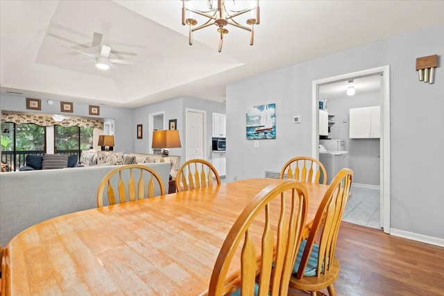 1025 Scaup Ct, Kiawah Island, SC 29455 - dining space featuring wood finished floors, washer / dryer, a chandelier, a raised ceiling, and a ceiling fan
