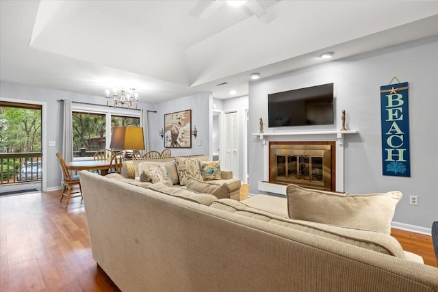 1025 Scaup Ct, Kiawah Island, SC 29455 - living room with wood finished floors, a chandelier, a glass covered fireplace, lofted ceiling, and a ceiling fan