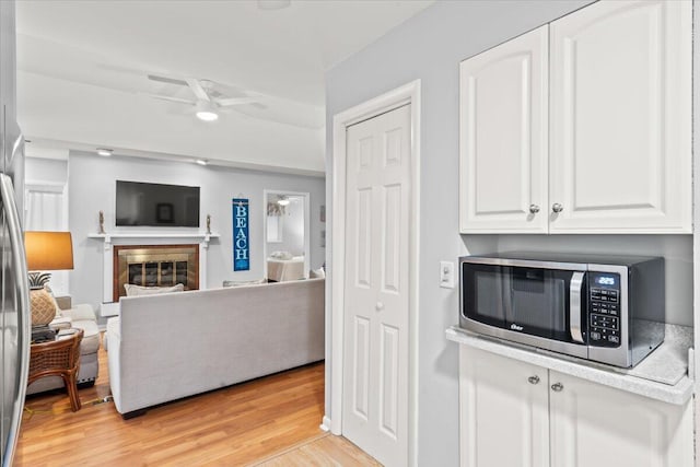 1025 Scaup Ct, Kiawah Island, SC 29455 - kitchen with stainless steel microwave, ceiling fan, open floor plan, white cabinets, and light wood-style floors