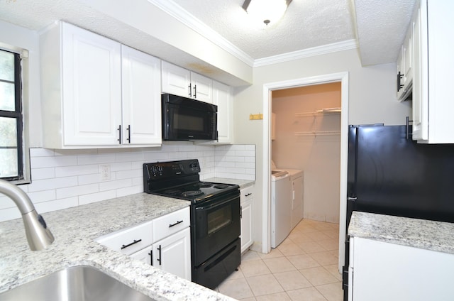 kitchen featuring a textured ceiling, black appliances, washer and clothes dryer, and decorative backsplash