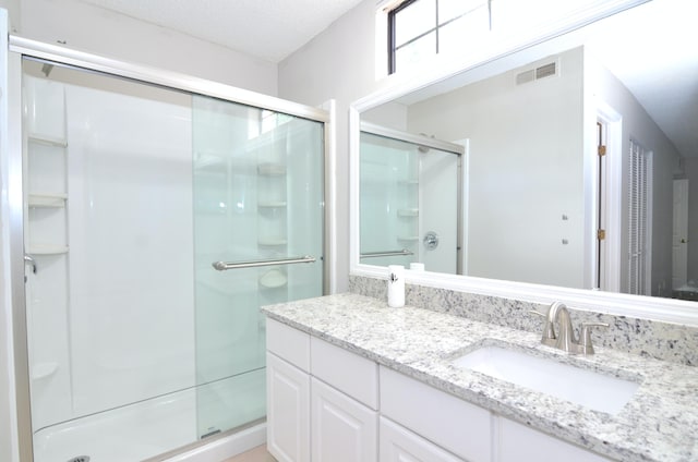 bathroom with vanity, a textured ceiling, and a shower with door