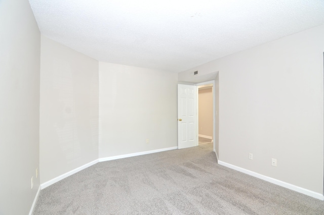 unfurnished room featuring light carpet and a textured ceiling