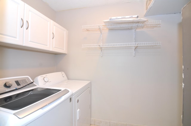 clothes washing area featuring tile patterned floors, cabinets, and washer and dryer