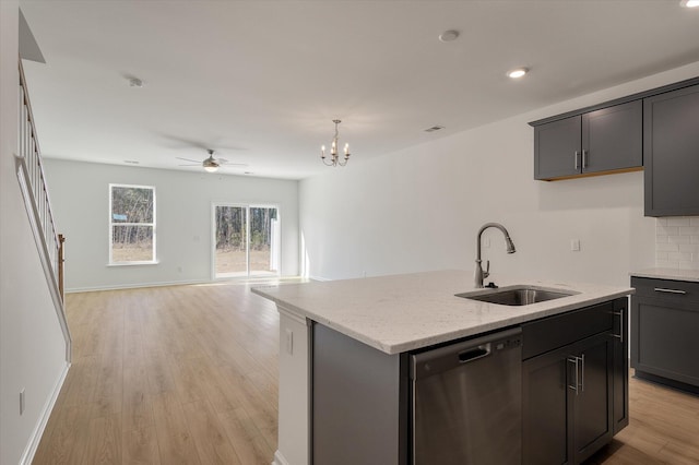 kitchen with a center island with sink, dishwasher, open floor plan, light stone countertops, and a sink