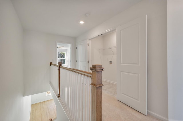 hall with recessed lighting, an upstairs landing, and baseboards