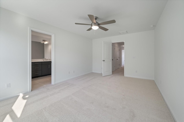 unfurnished bedroom featuring light colored carpet, a sink, visible vents, baseboards, and ensuite bath