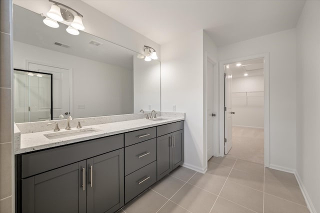 bathroom featuring visible vents, double vanity, a sink, and a walk in closet